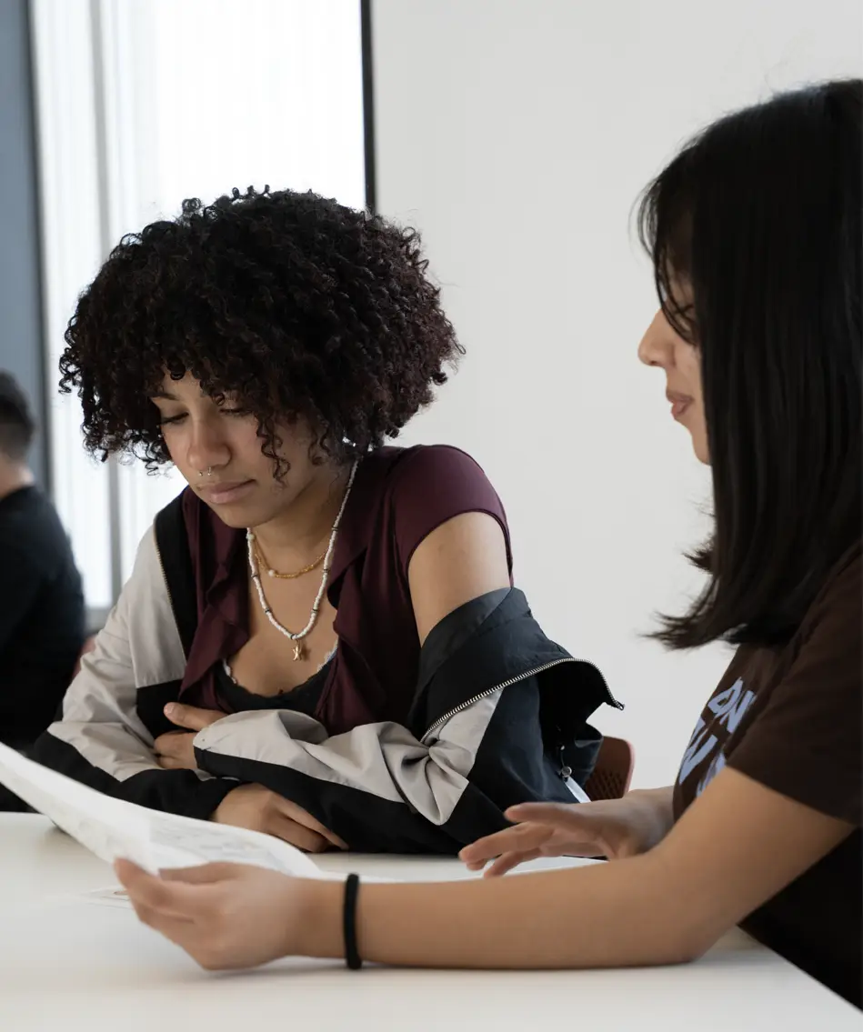 Dos alumnas revisando la documentación de admisión junto a la secretaría del centro de formación profesional Nova FP23 en Madrid.