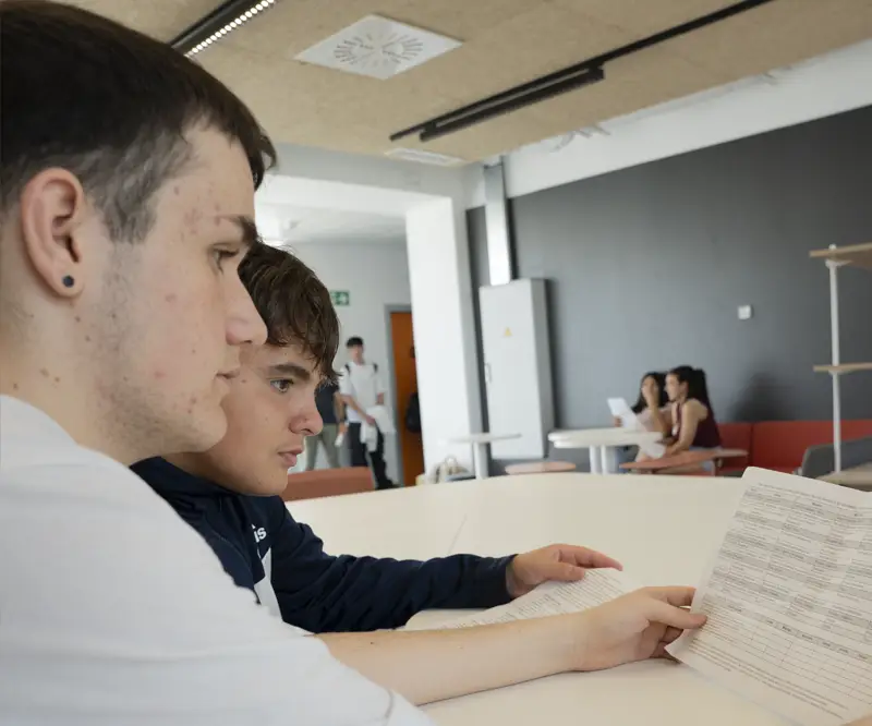 Dos alumnos consultando los requisitos e información para solicitar las becas de FP de la Comunidad de Madrid en el centro Nova FP23.