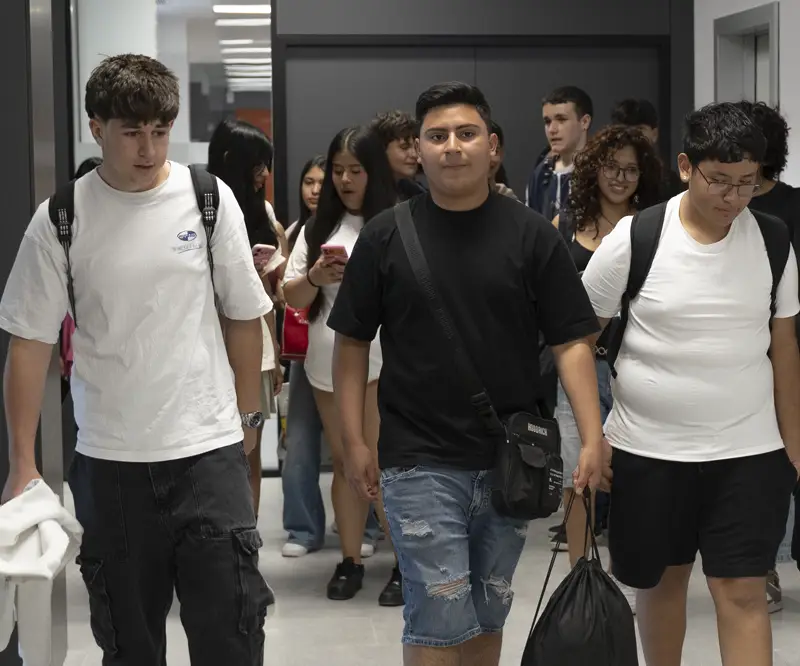 Grupo de estudiantes caminando por el pasillo del centro Nova FP23 en Madrid, dirigiéndose a la secretaría durante el horario de atención.