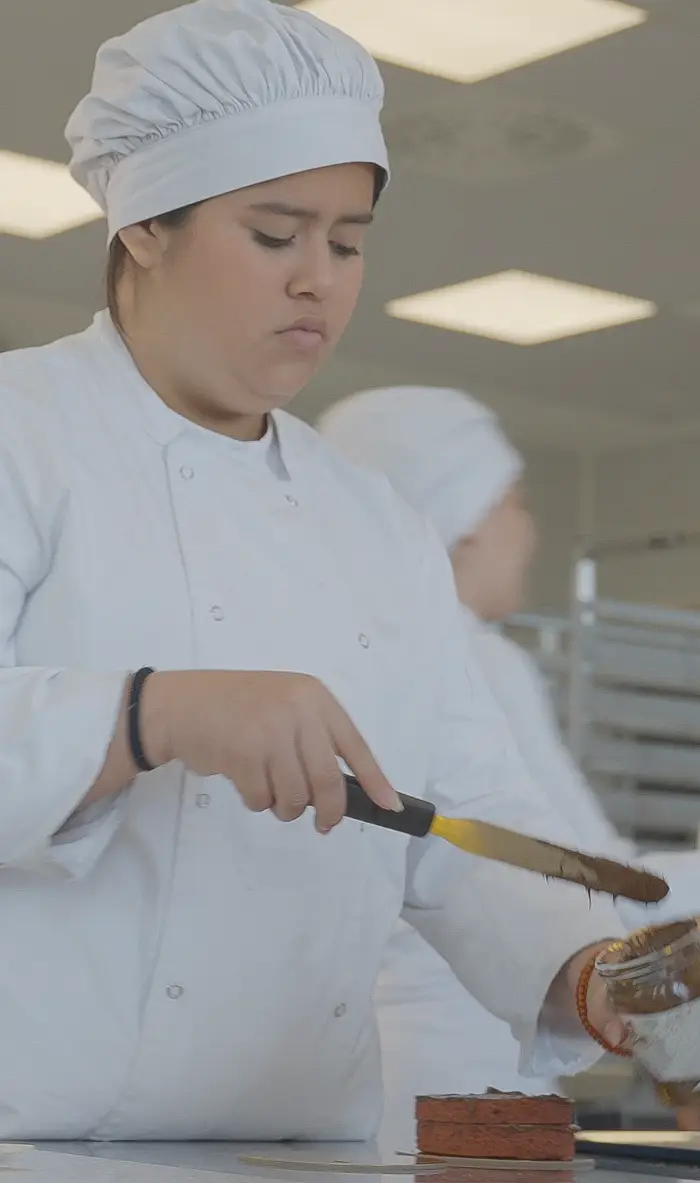 Alumna del título de Técnico Básico en Actividades de Panadería y Pastelería utilizando una espátula en el obrador de la escuela Nova FP23 en Madrid