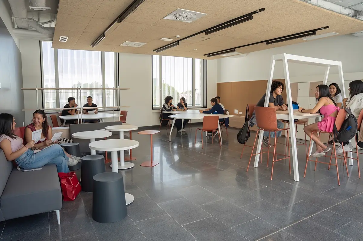 Grupos de estudiantes interactuando y estudiando en las zonas comunes y áreas de descanso del campus de formación profesional Nova FP23 en Madrid